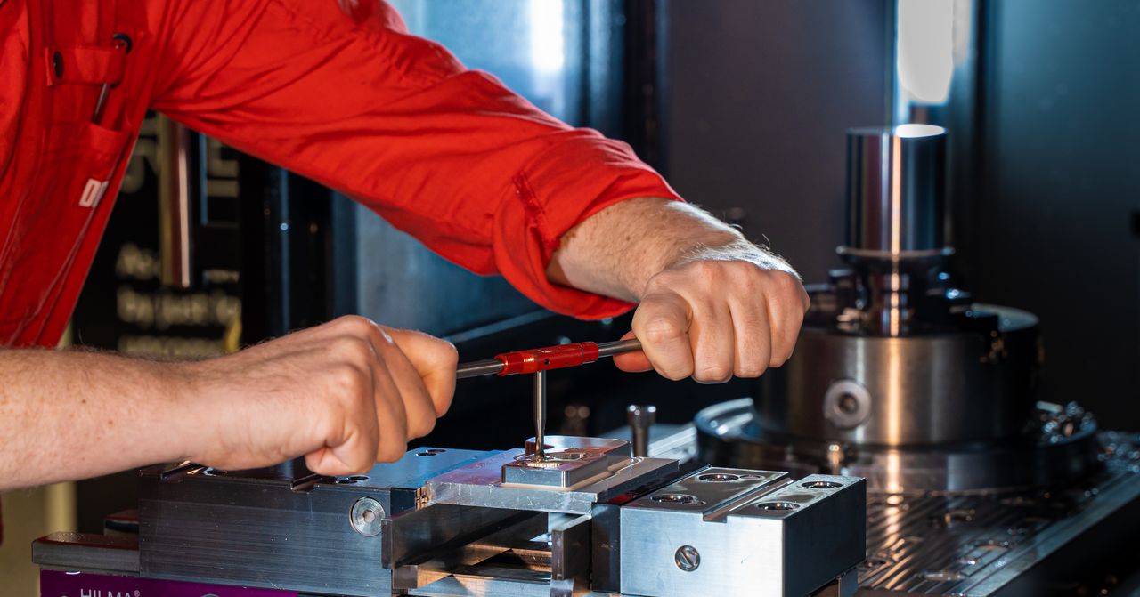 Hands working on industrial machinery with precision tools, showcasing engineering skills.